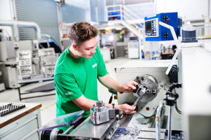 Lehrling arbeitet an Drehmaschine